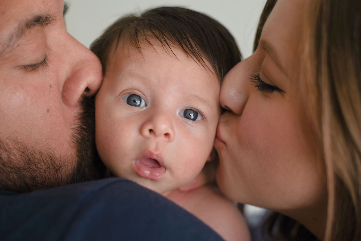 Intimate family moment captured in close-up against neutral background.