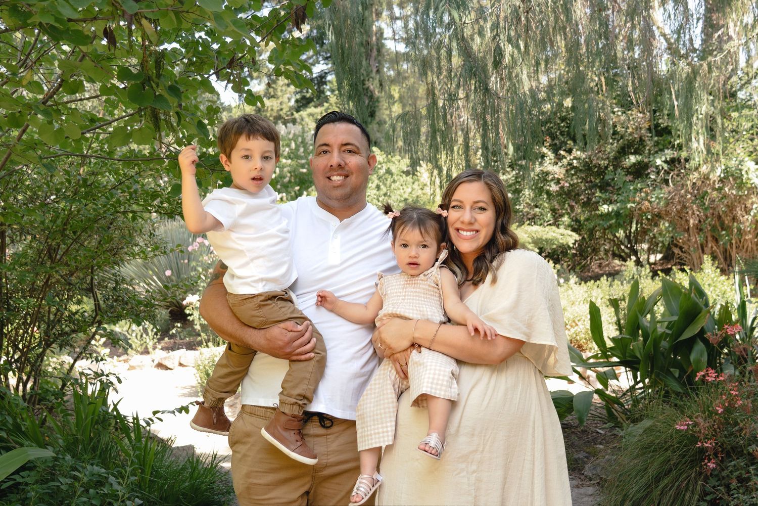 A family enjoys quality time together in a lush outdoor garden setting with tropical plants and trees.