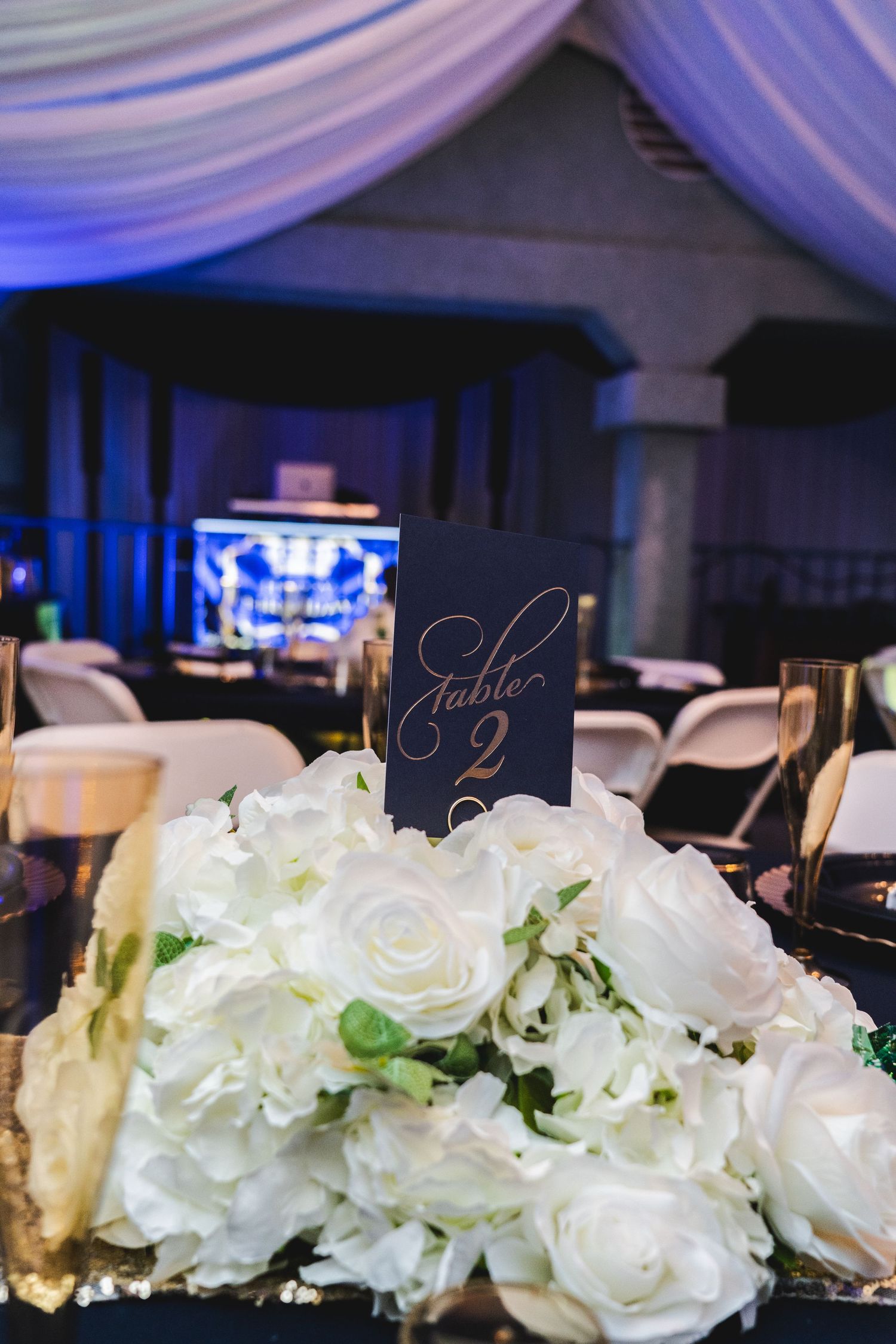 White floral table decorations with navy blue accents for an elegant event setting.