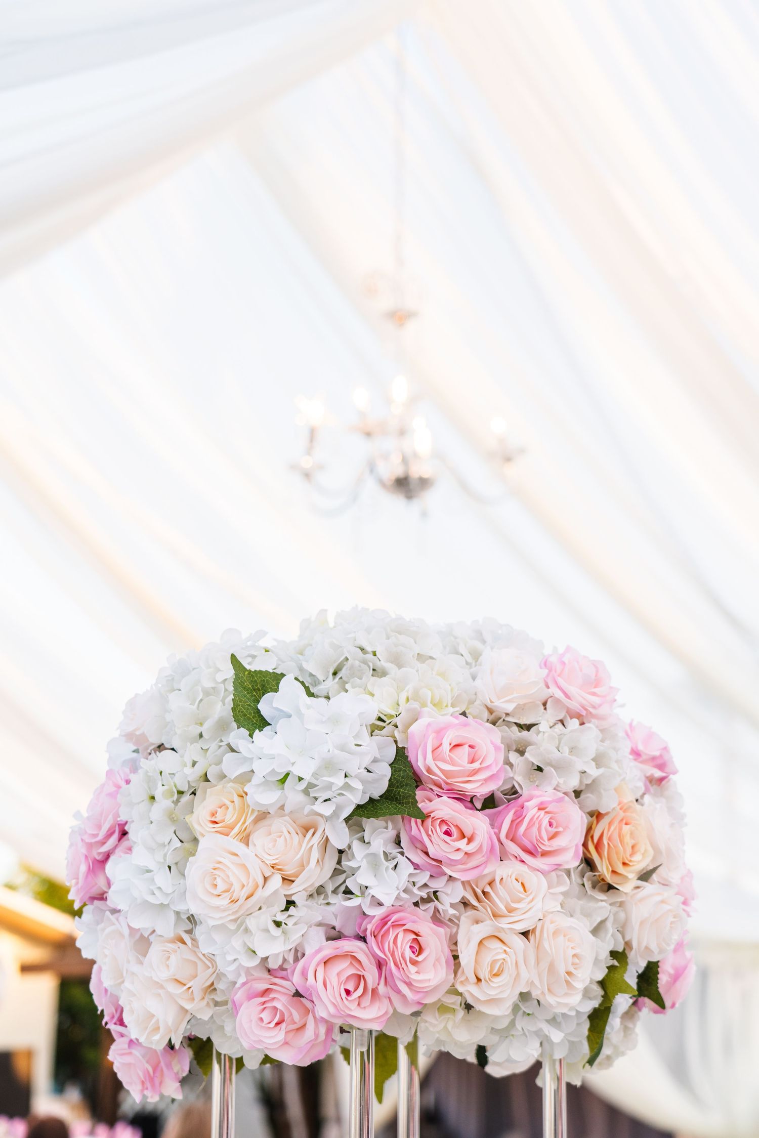 Lush floral arrangement of pink and white roses against white tent fabric backdrop.