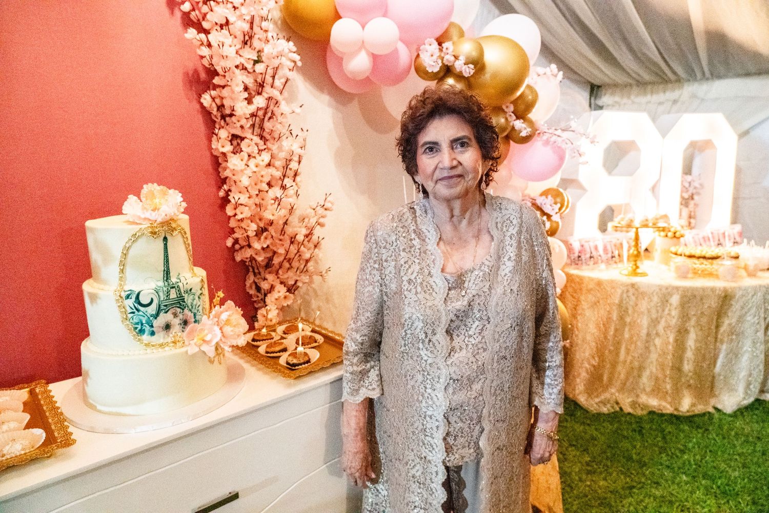 Elegant party setup with pink and gold decorations and a white cake.