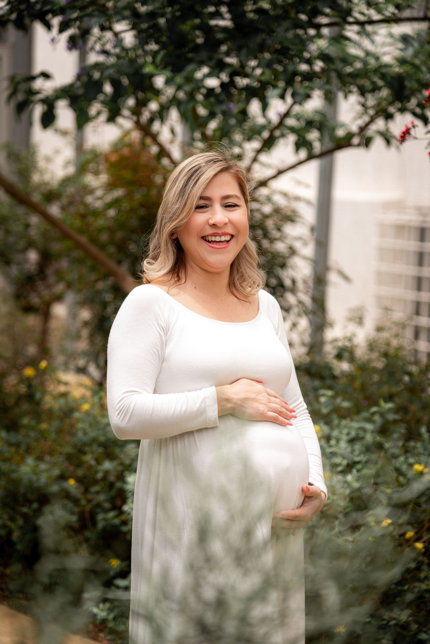 A glowing maternity portrait in a garden setting with soft natural light.