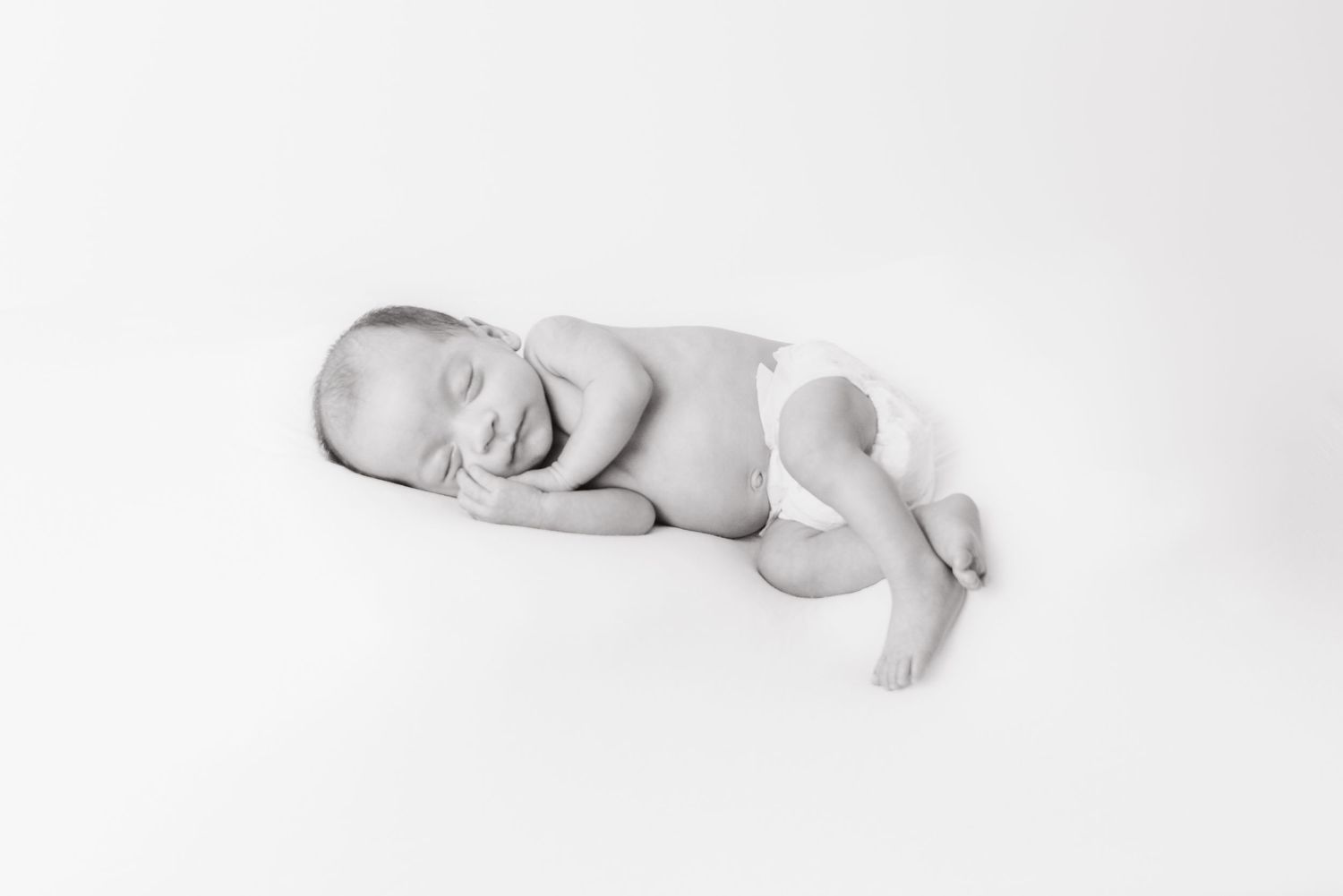High key black and white newborn photography showing gentle side profile.