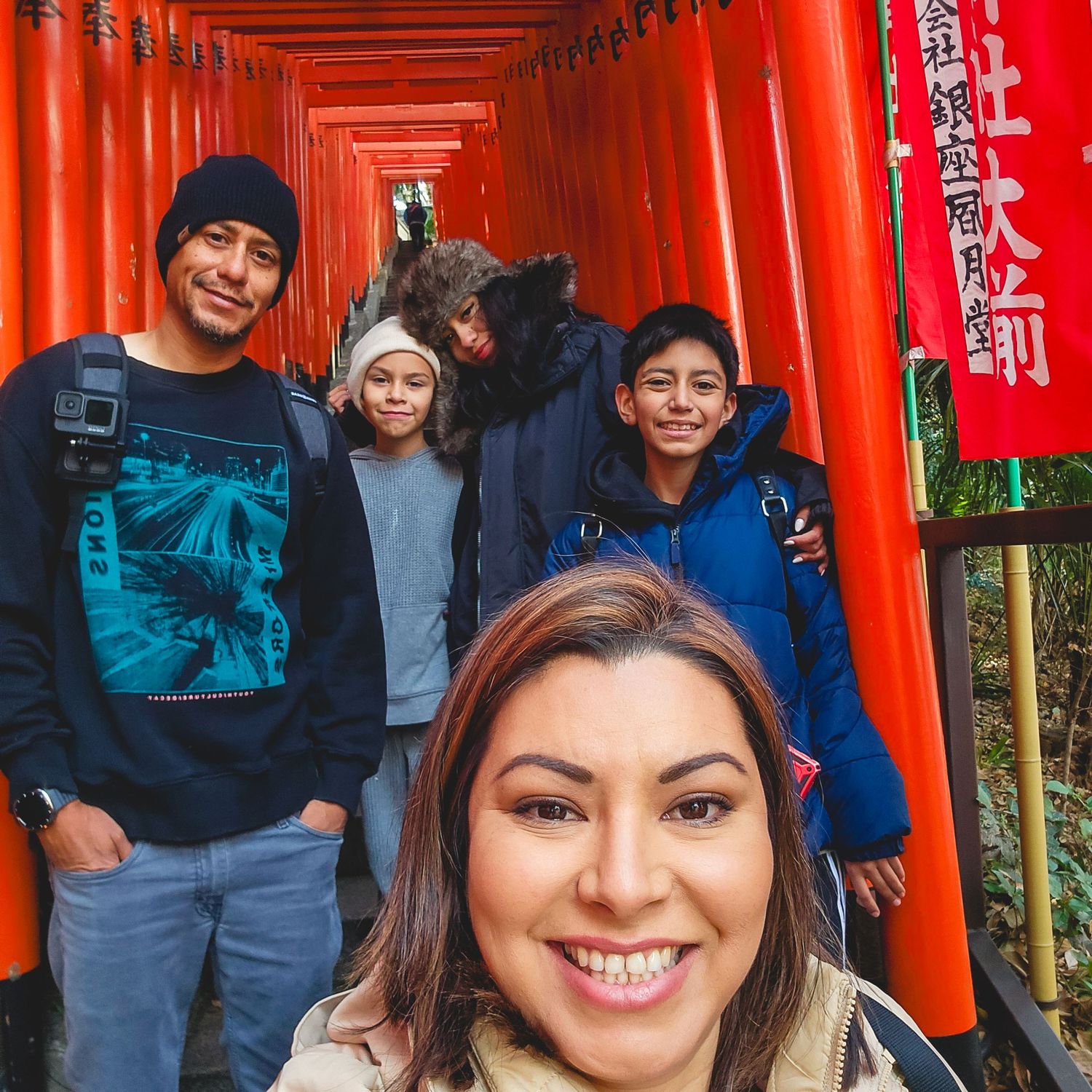 Group photo under vibrant red torii gates at Japanese shrine.