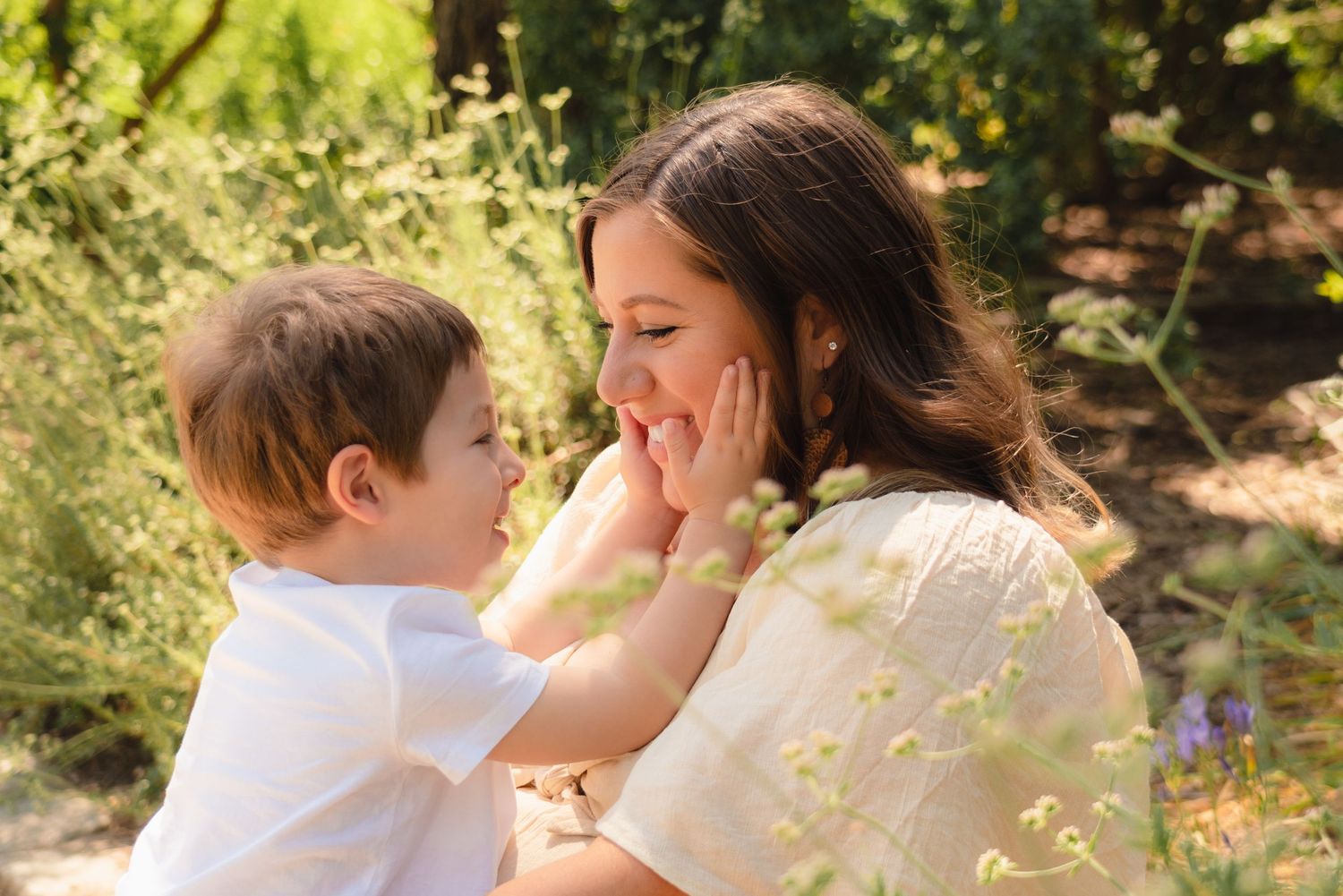 Sunlit portraits of tender moments between a parent and child in a lush garden setting.