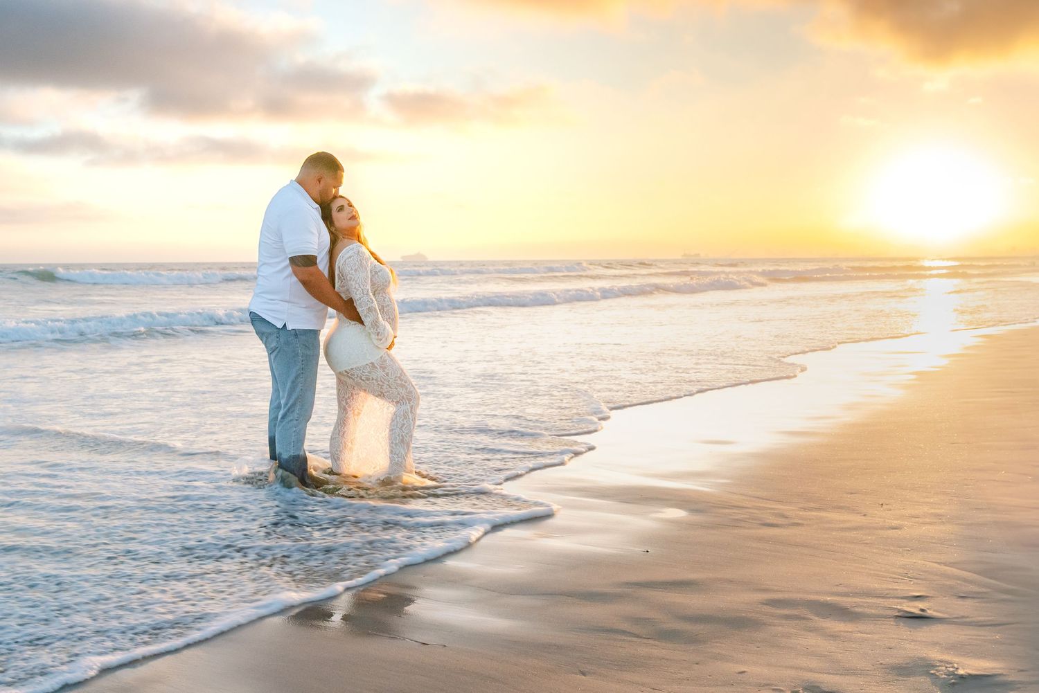 Beach maternity photography session during golden hour with waves in background.