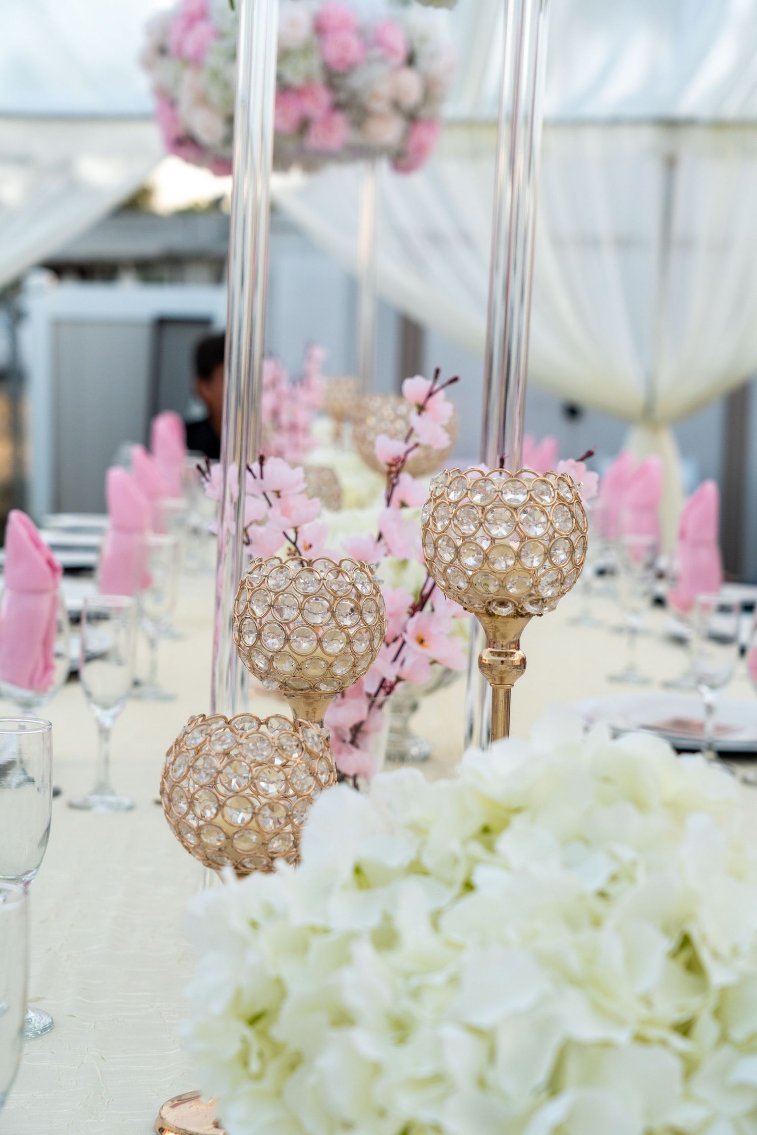 Elegant wedding reception table with crystal candle holders and pink cherry blossom centerpieces.