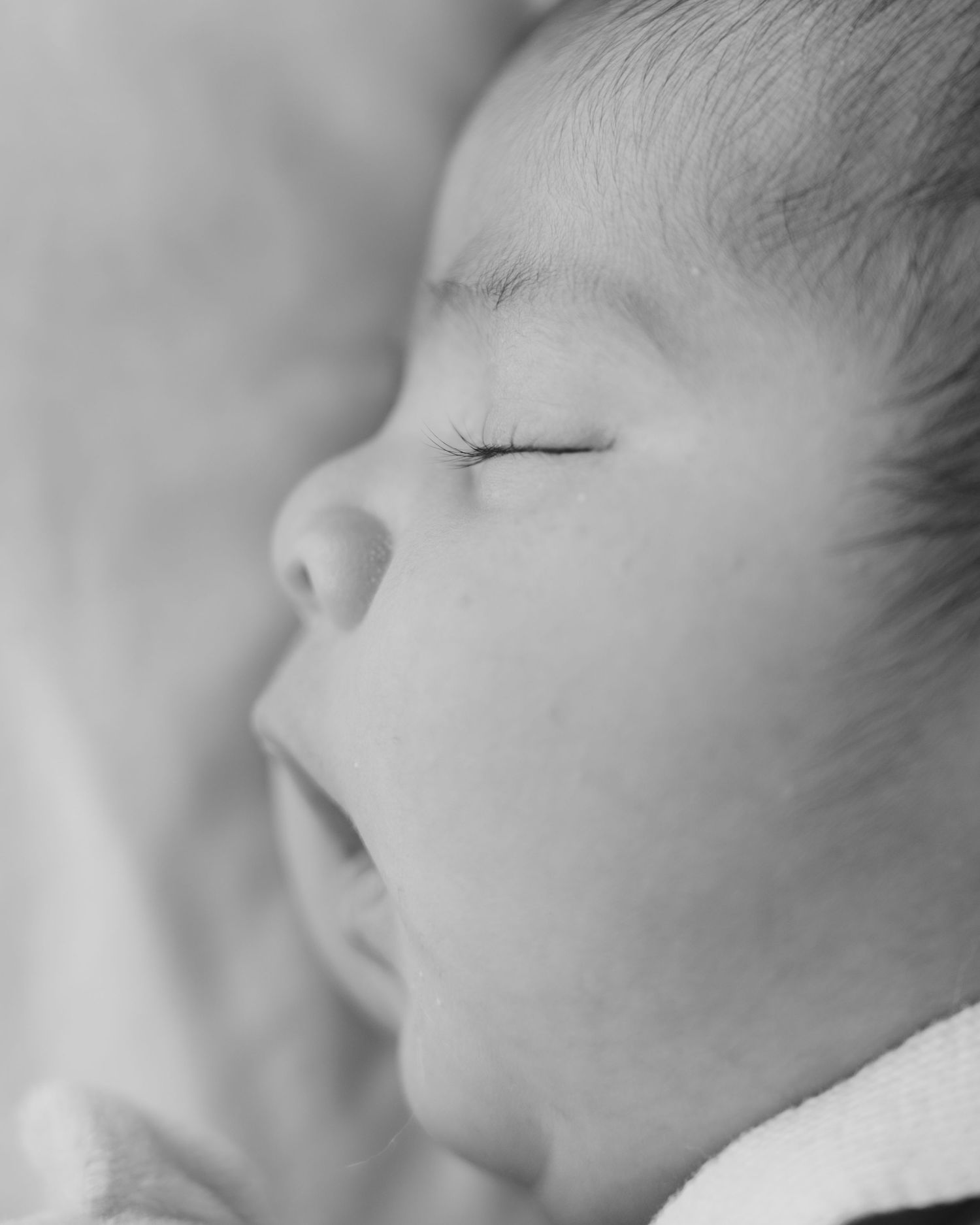Black and white close-up portrait of a sleeping newborn baby with delicate features and soft skin.