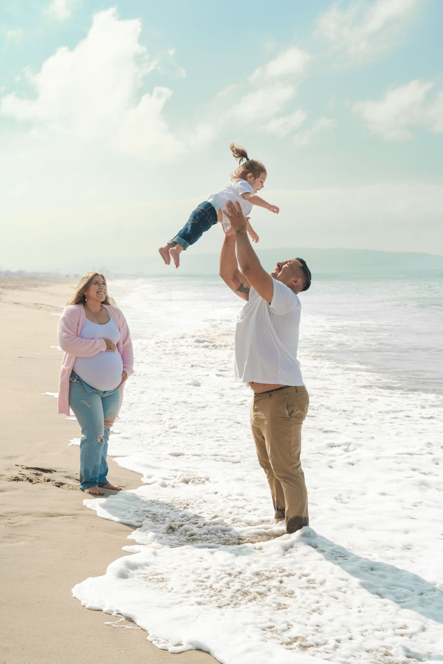Joyful beach photoshoot with people playing and jumping in the ocean waves.