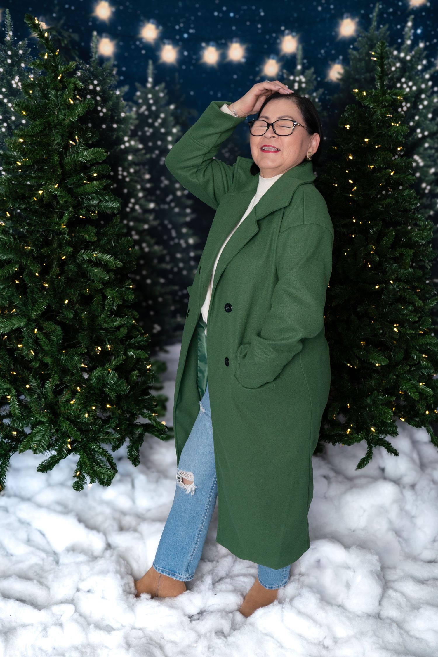 Winter portrait scene with green coat against snowy backdrop and twinkling holiday lights.