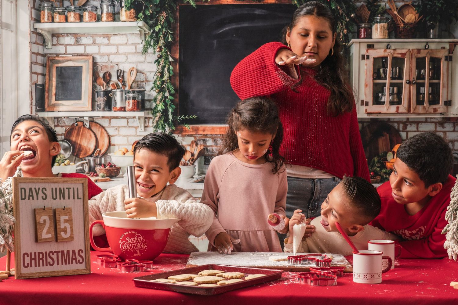 A festive family gathering around a red tablecloth with Christmas cookies and decorations during holiday celebrations.