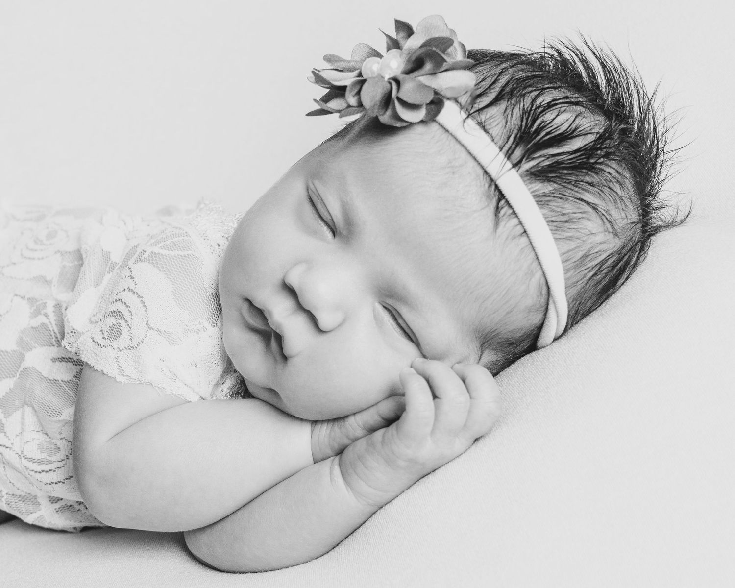 A delicate series of four black and white portraits capturing a small infant sleeping peacefully on textured bedding.