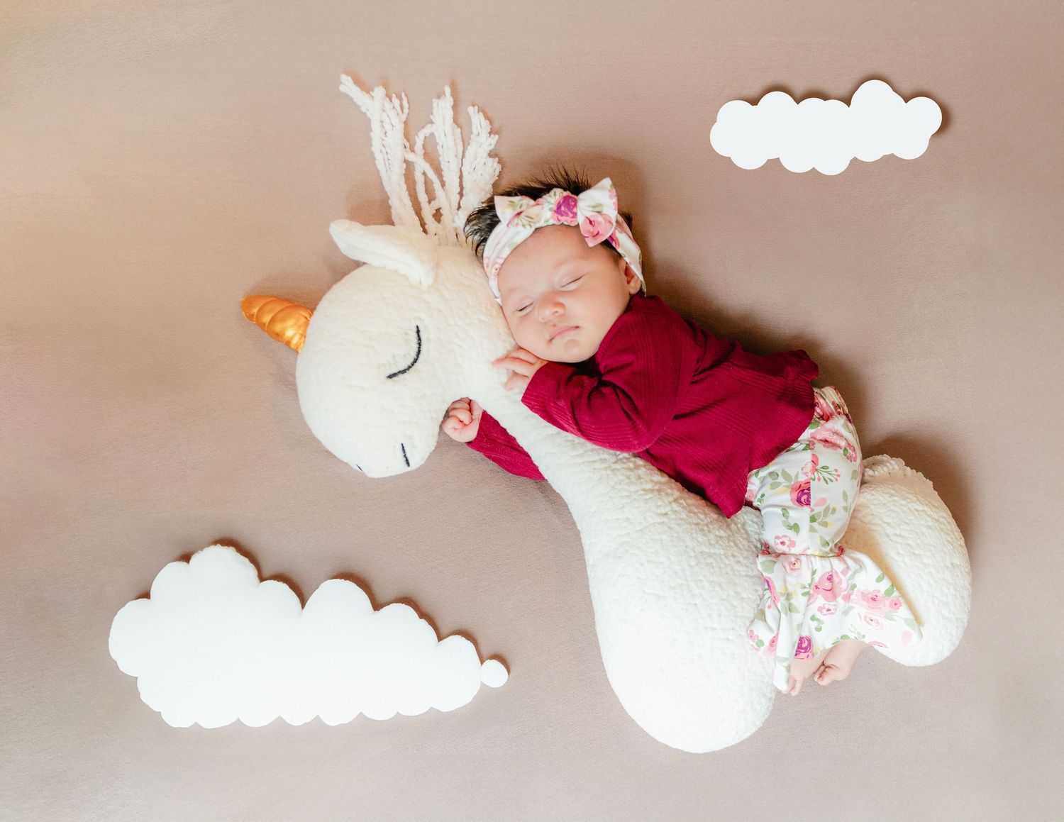 Baby nursery scene with plush toys and white decorative clouds against neutral background.