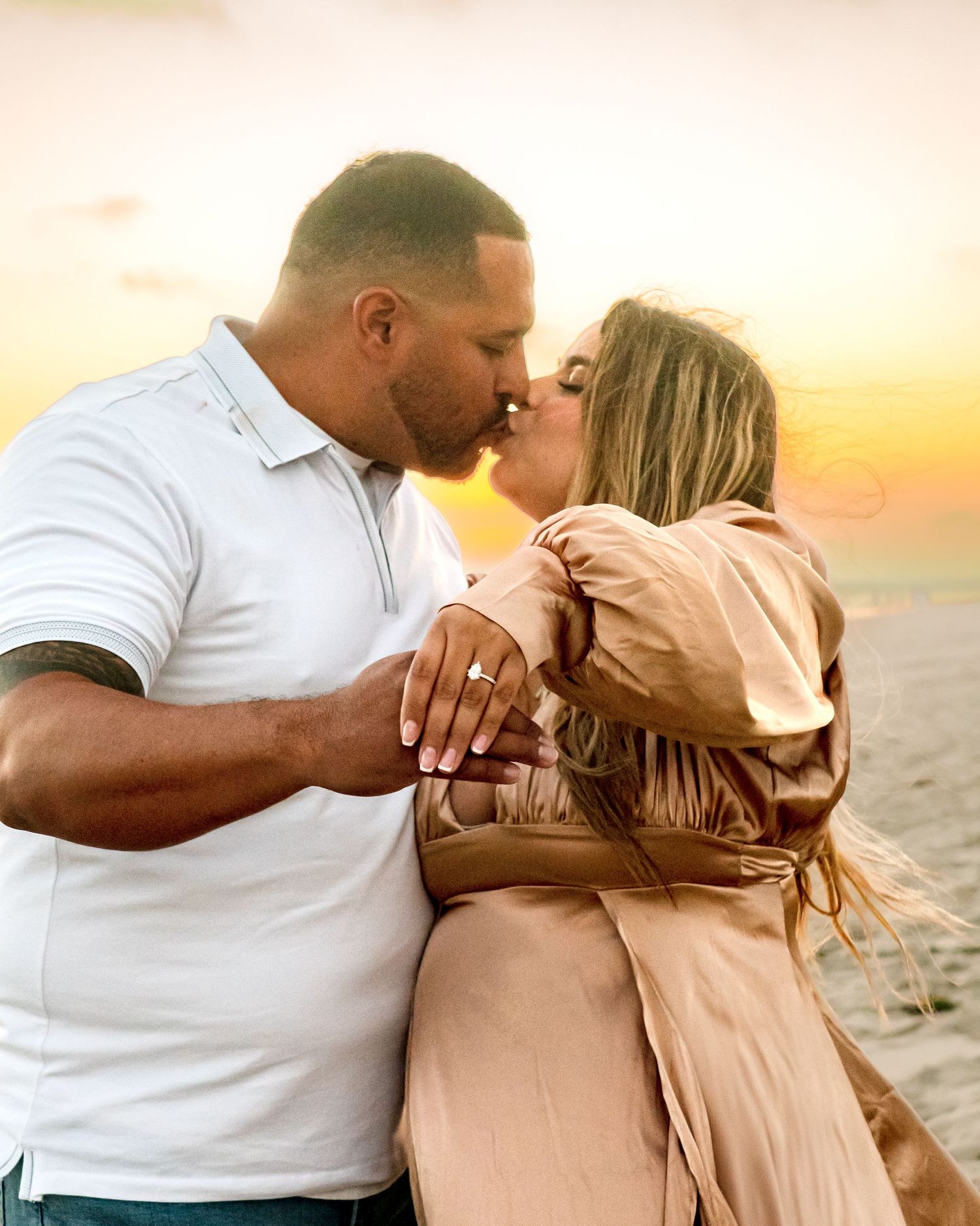 Romantic moment shared between couple on beach at sunset after proposal.