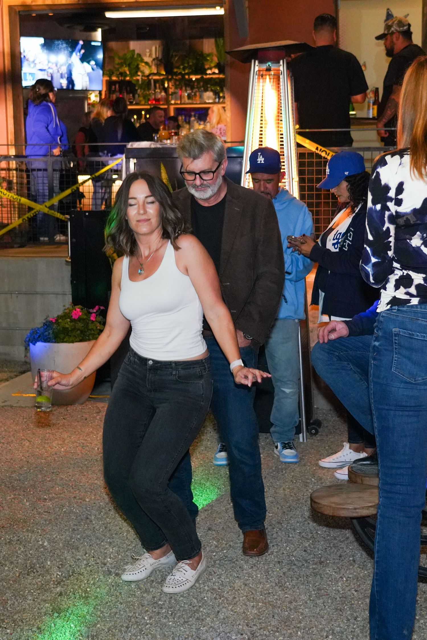 Couple dancing together at an outdoor bar patio event at night.