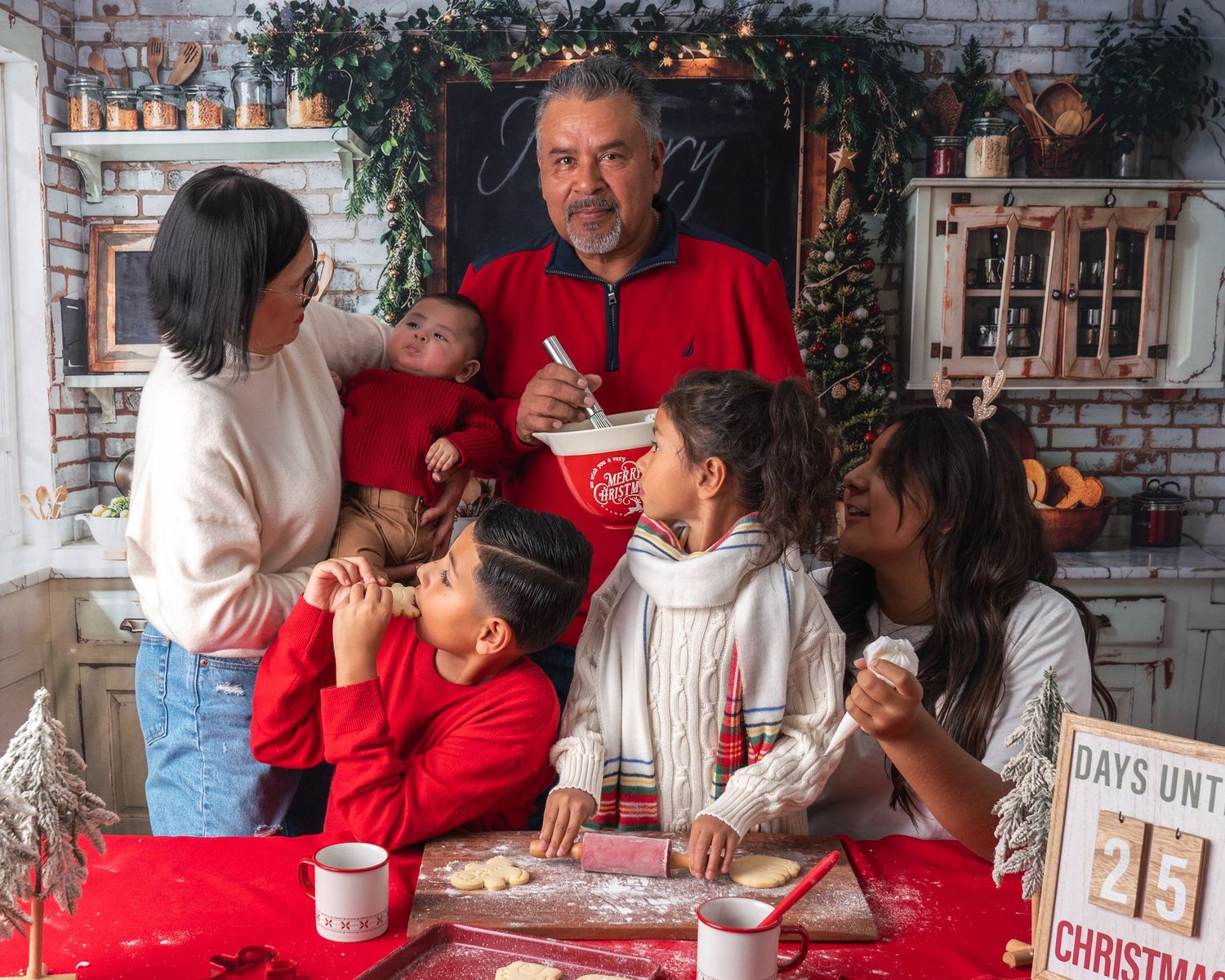 Holiday cookie decorating scene with family members wearing red and white around kitchen table.