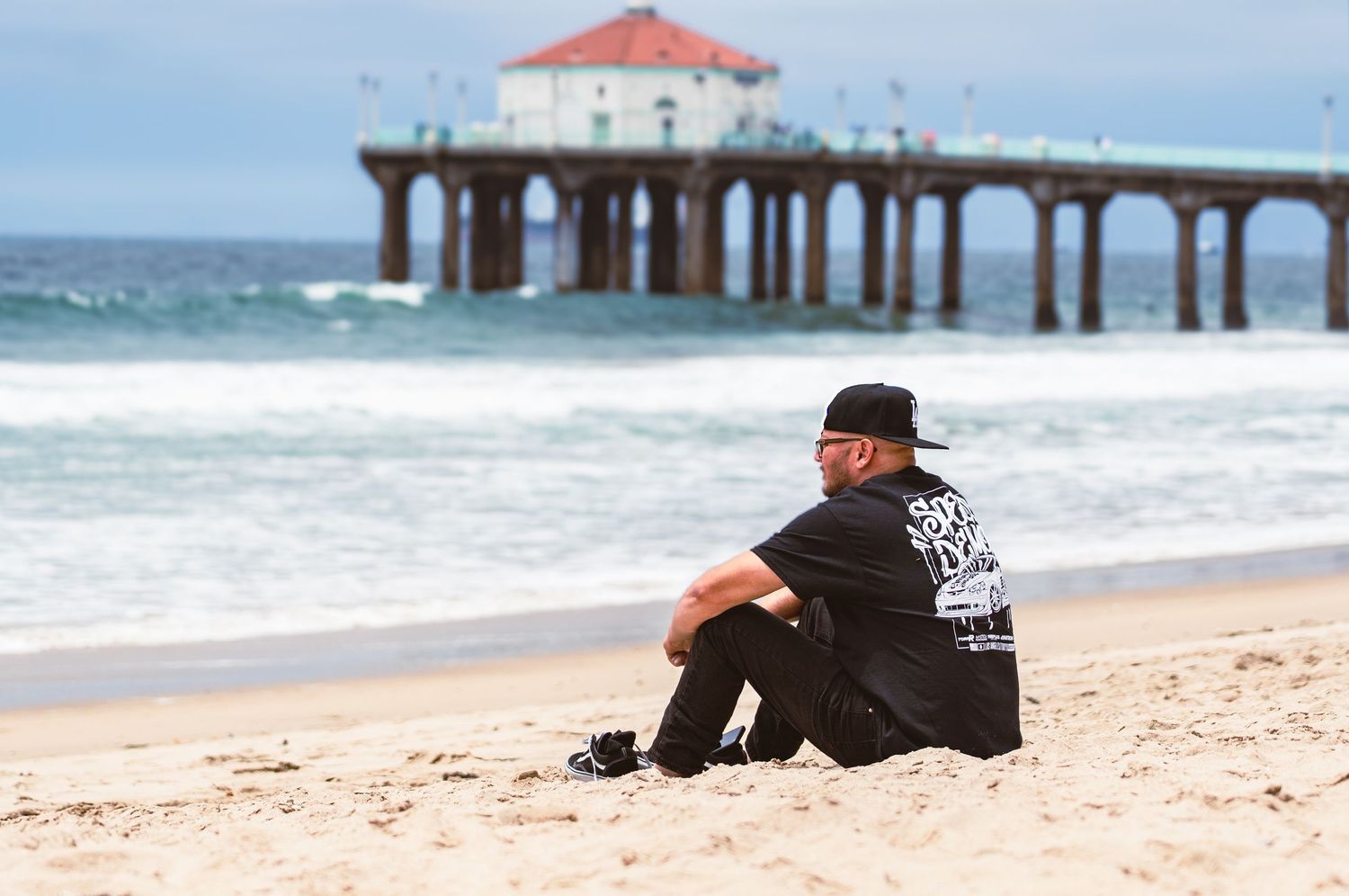 A series of beach scenes showing a pier and someone sitting on the sand looking out at the ocean waves.