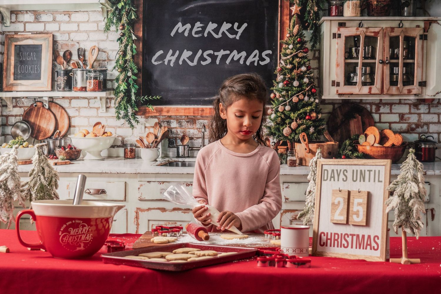 A cozy Christmas kitchen scene with a red tablecloth, chalkboard sign, and rustic decor while someone writes at the table.