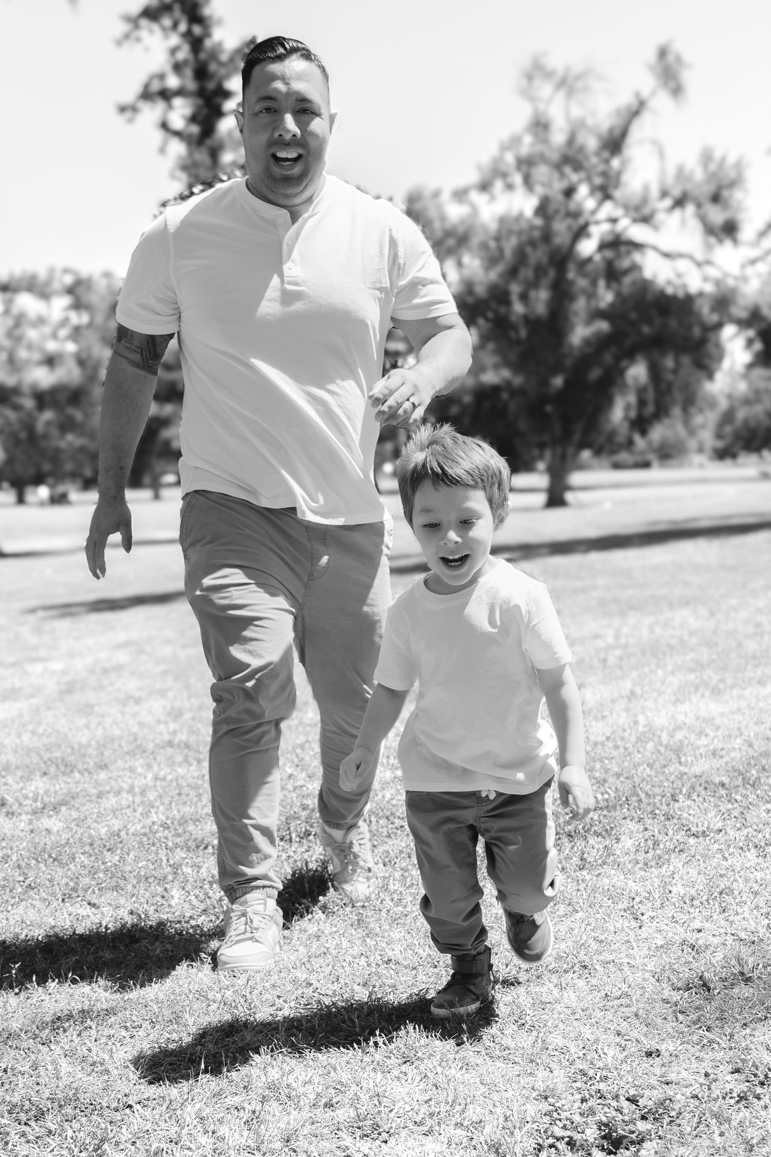 Running and playing together on sunny grass in black and white photography.
