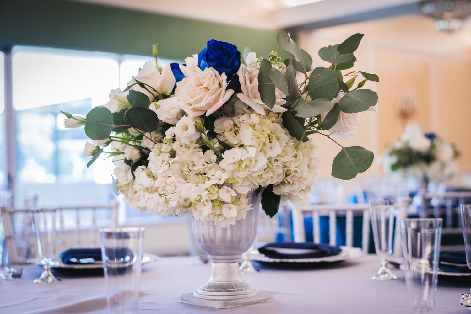 Elegant table setting with white floral arrangements and silver charger plates.