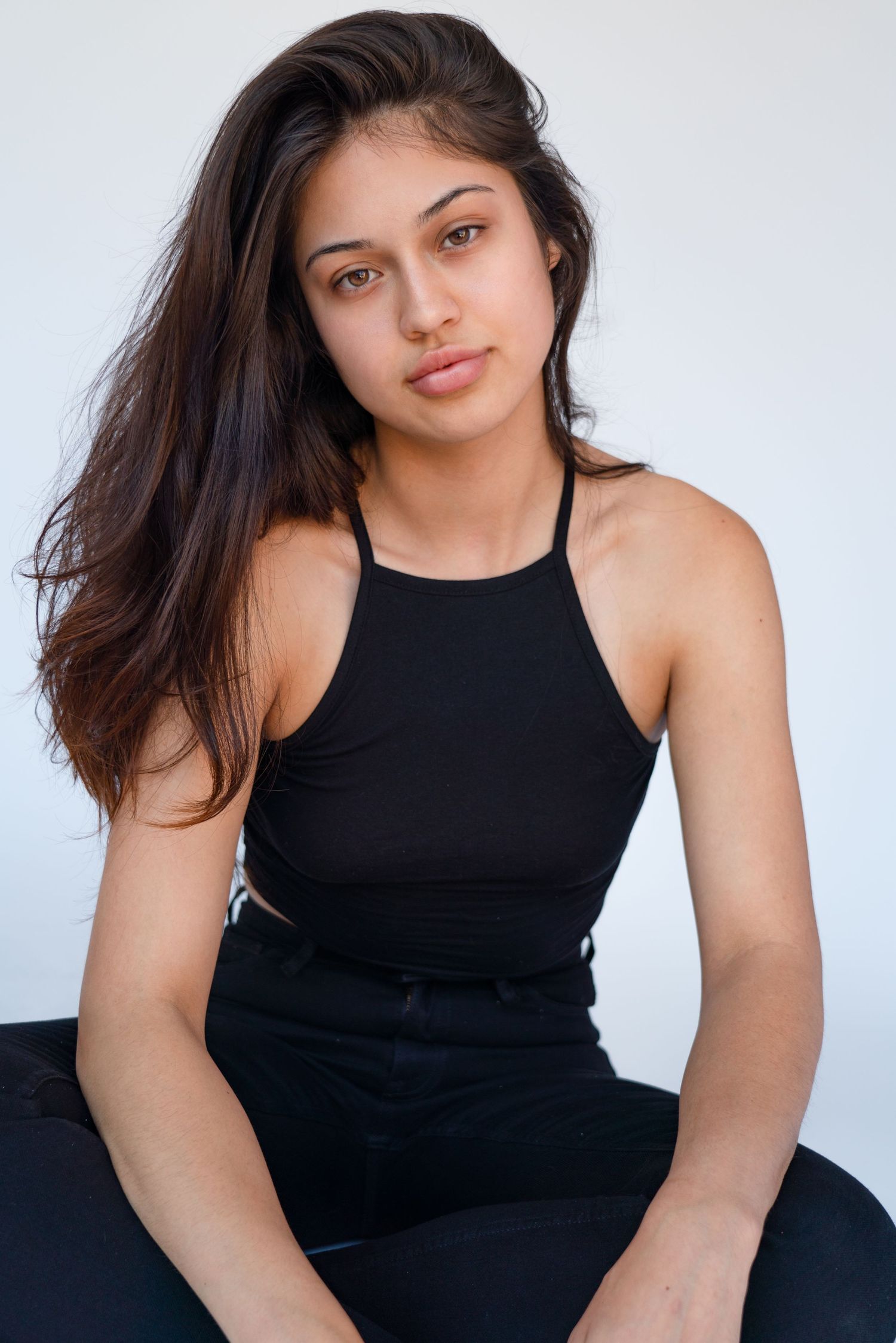A portrait in a black halter top against a white studio backdrop.