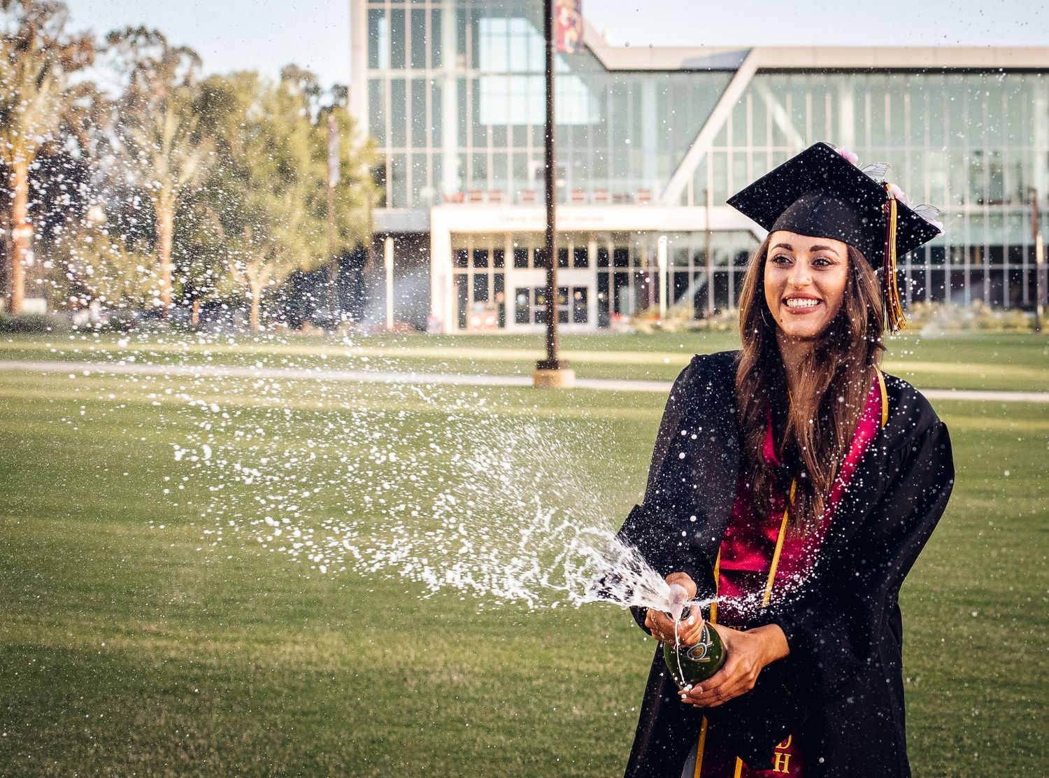 Champagne celebration sequence with graduate on university grounds.