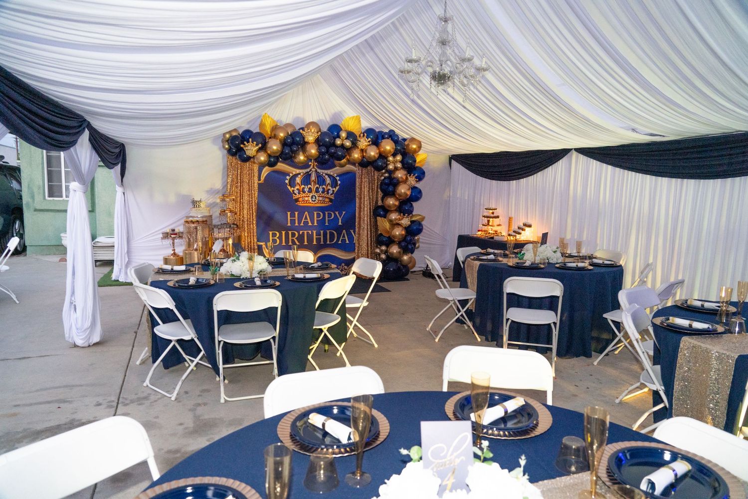 White folding chairs arranged in rows under draped white tent ceiling for an event.