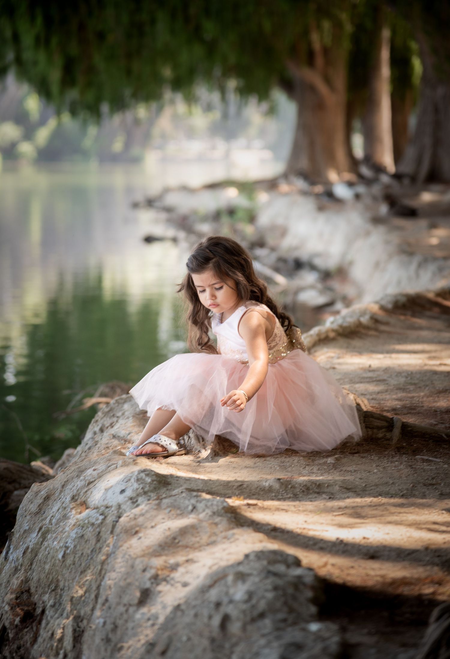 A dreamy sequence of photos showing a figure in a pink tulle dress reclining by a tranquil lakeside on a sunny day.