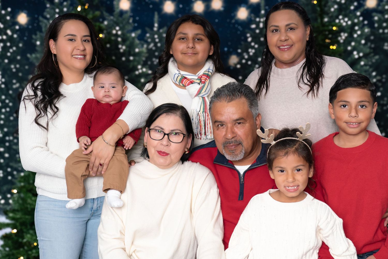 Holiday family portrait with coordinated red and white outfits against sparkly winter backdrop.