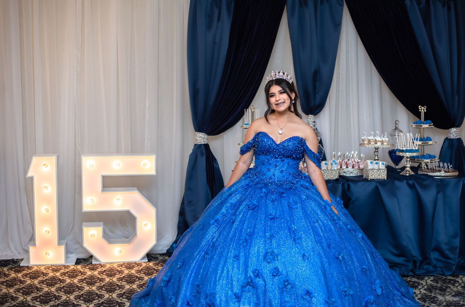 A stunning royal blue ballgown with intricate embellishments and sparkles fills the frame at a formal event.