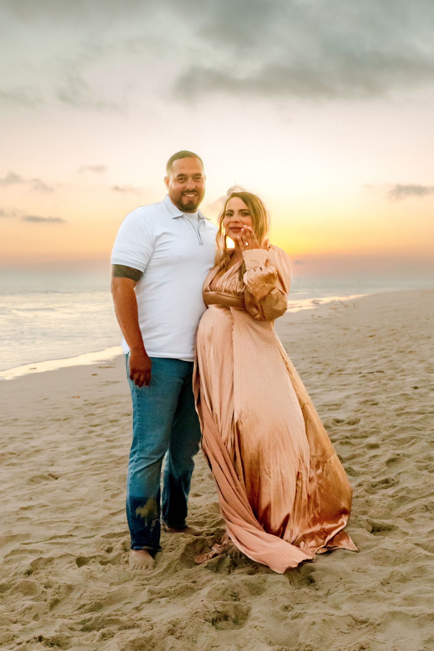 Newly engaged couple poses on beach at sunset after proposal.
