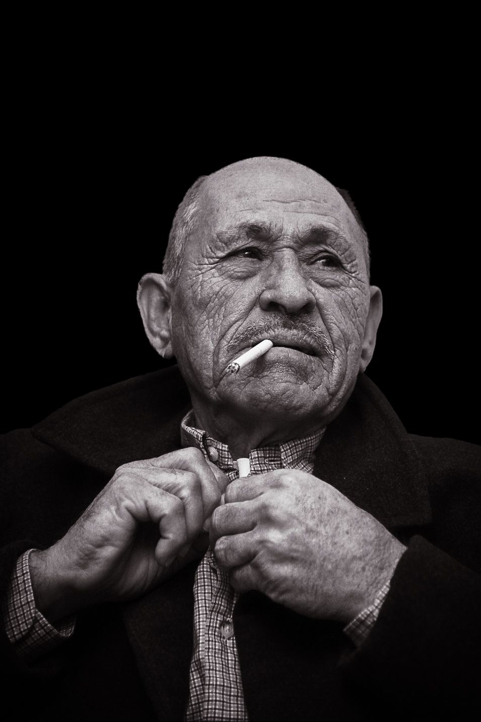 A series of black and white photos showing hands adjusting a checkered bowtie in dramatic lighting.
