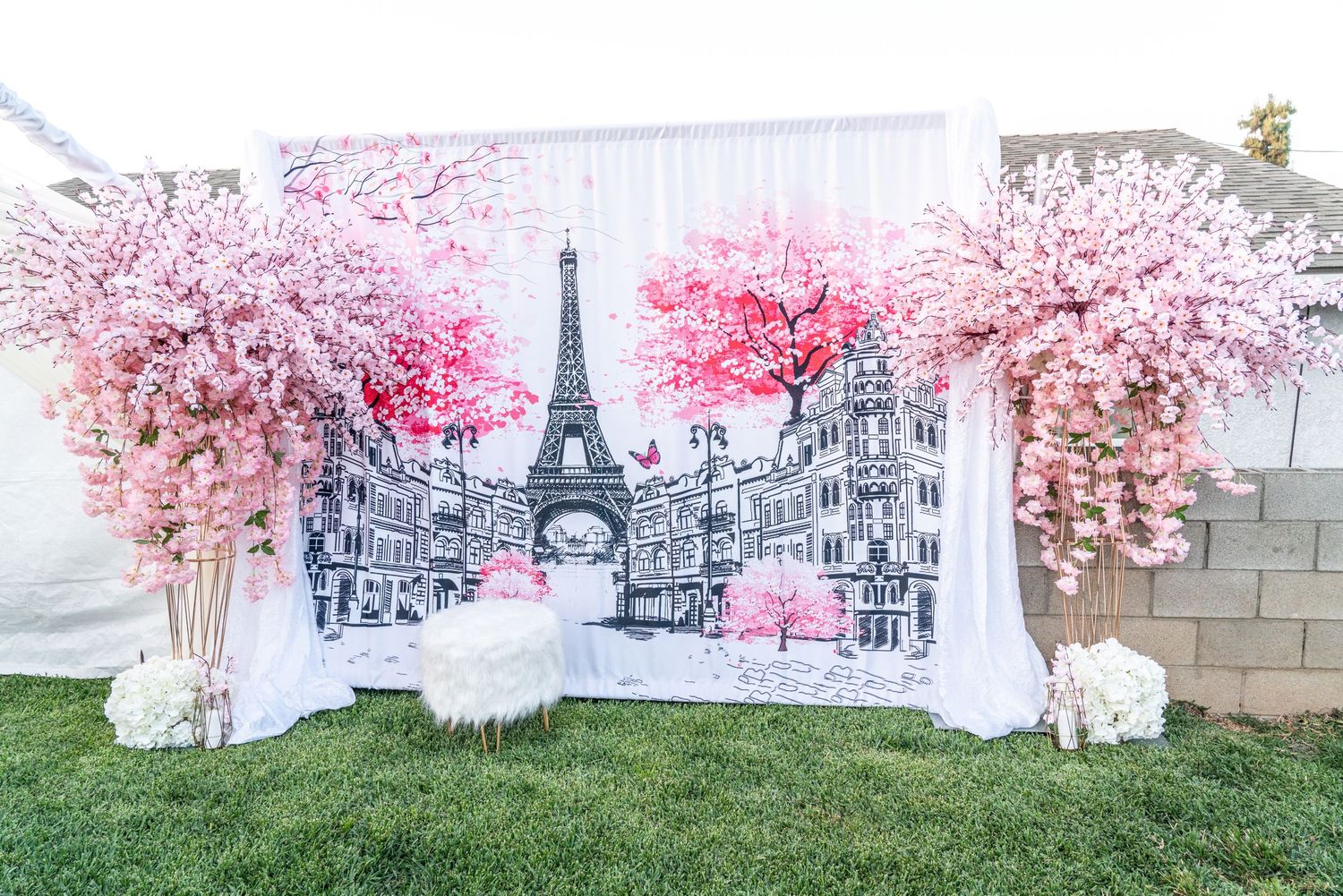Outdoor wedding venue decorated with pink cherry blossom trees and white chairs arranged for a ceremony.