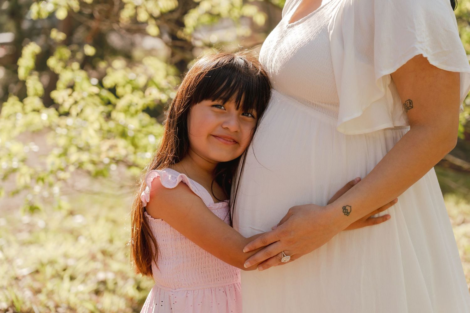 A touching family moment captured against a sunlit outdoor background.
