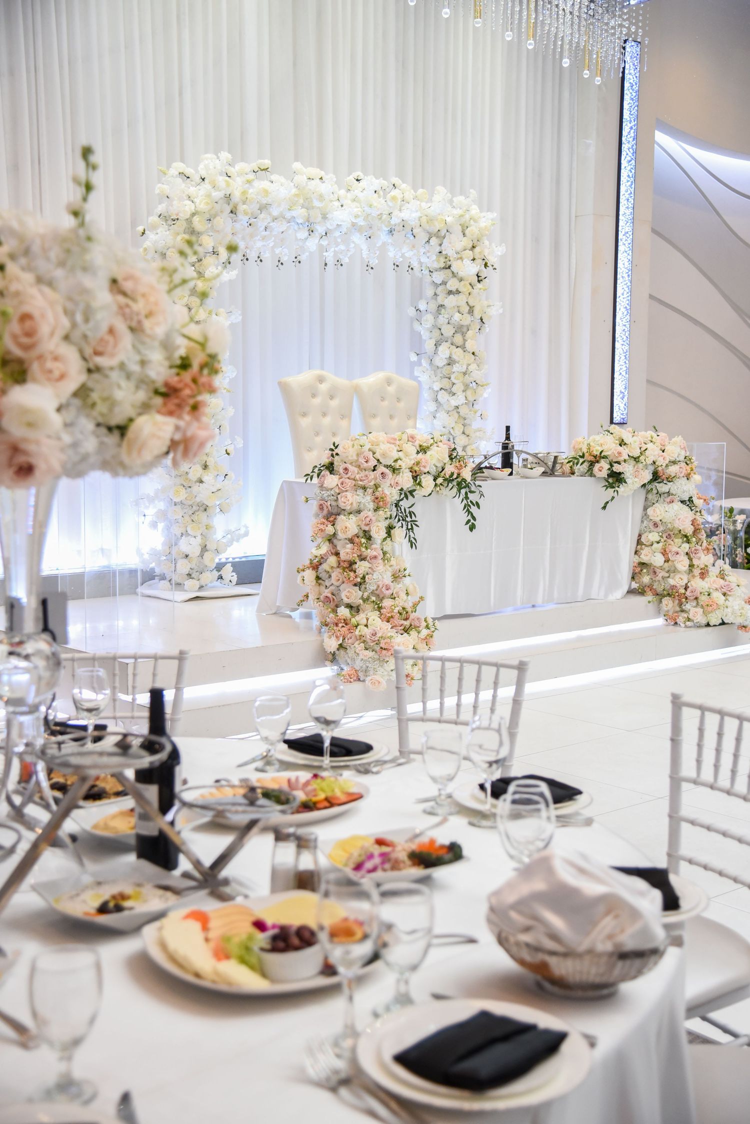 Elegant white and blush floral wedding reception tables with silver chiavari chairs and luxurious tall centerpieces.