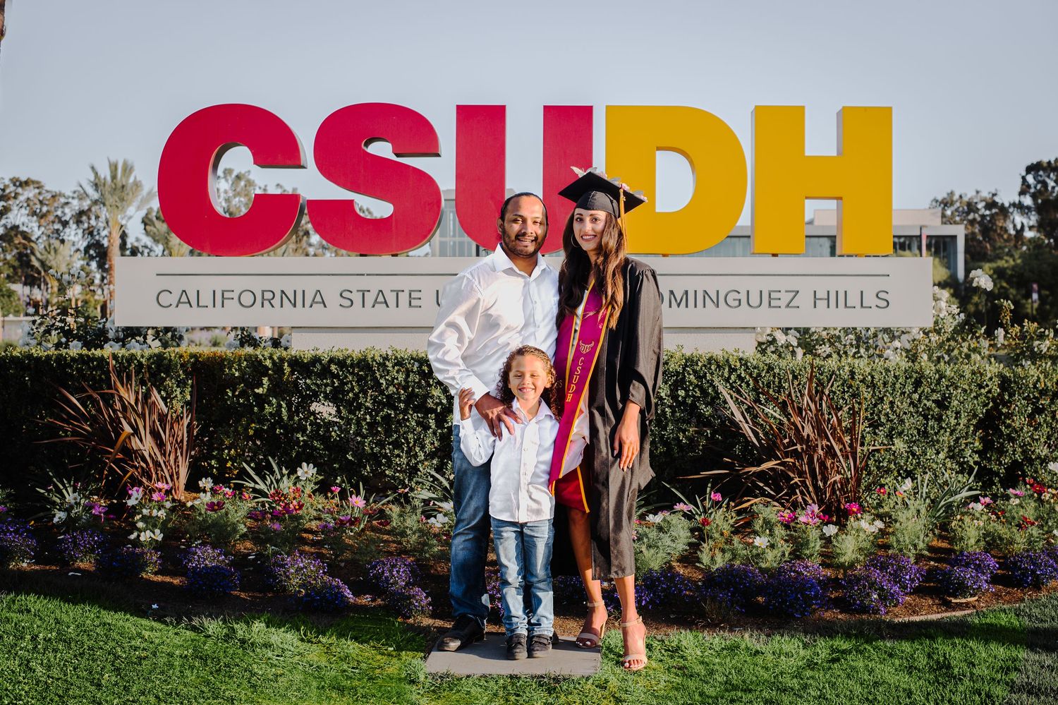 Family photos taken in front of CSUDH university campus sign and landscaping.