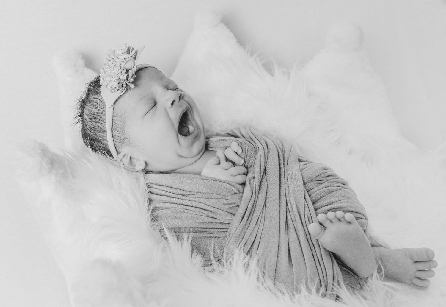 Artistic black and white photo of baby in ruffled outfit.