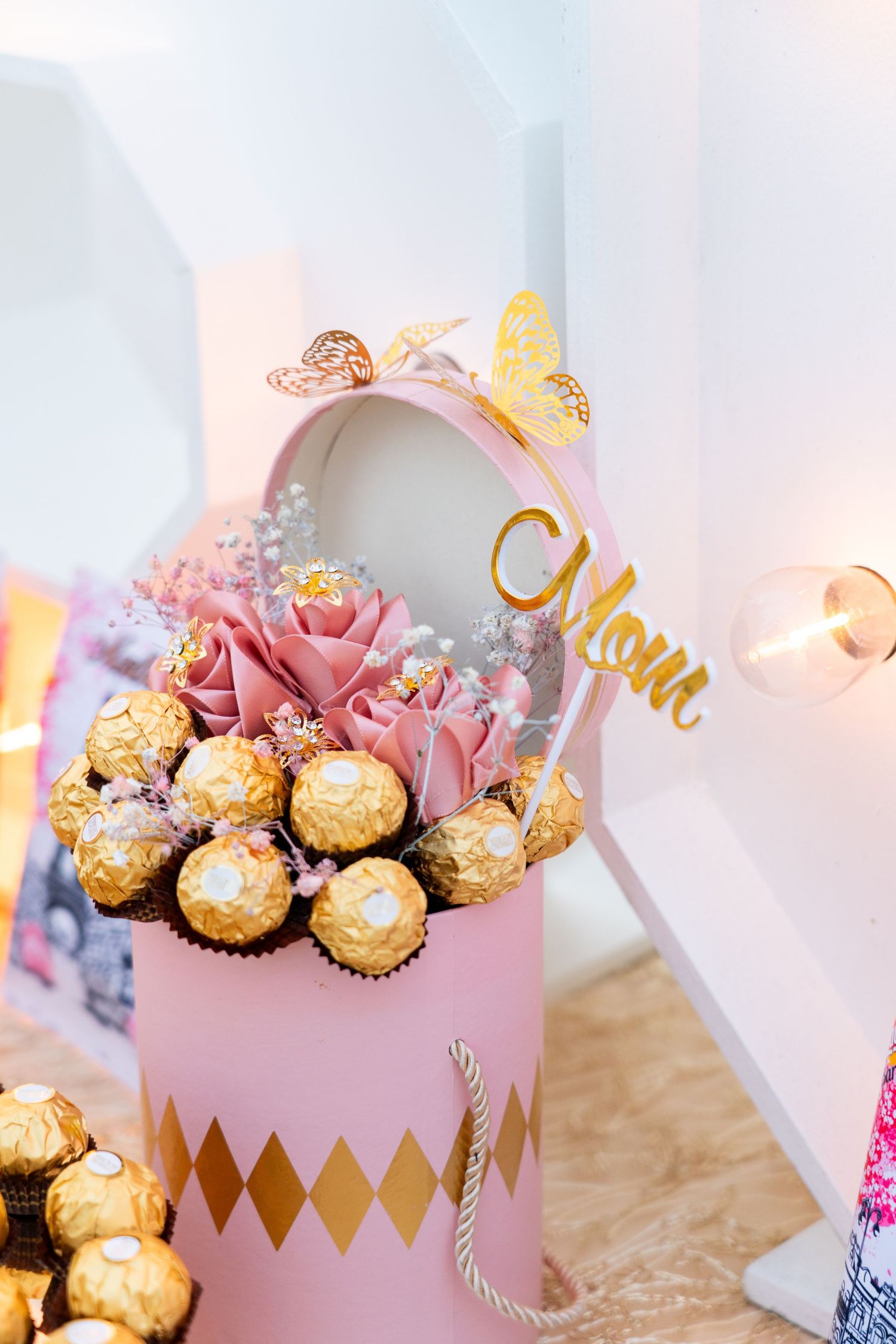 Pink and gold party favor boxes filled with Ferrero Rocher chocolates on display.