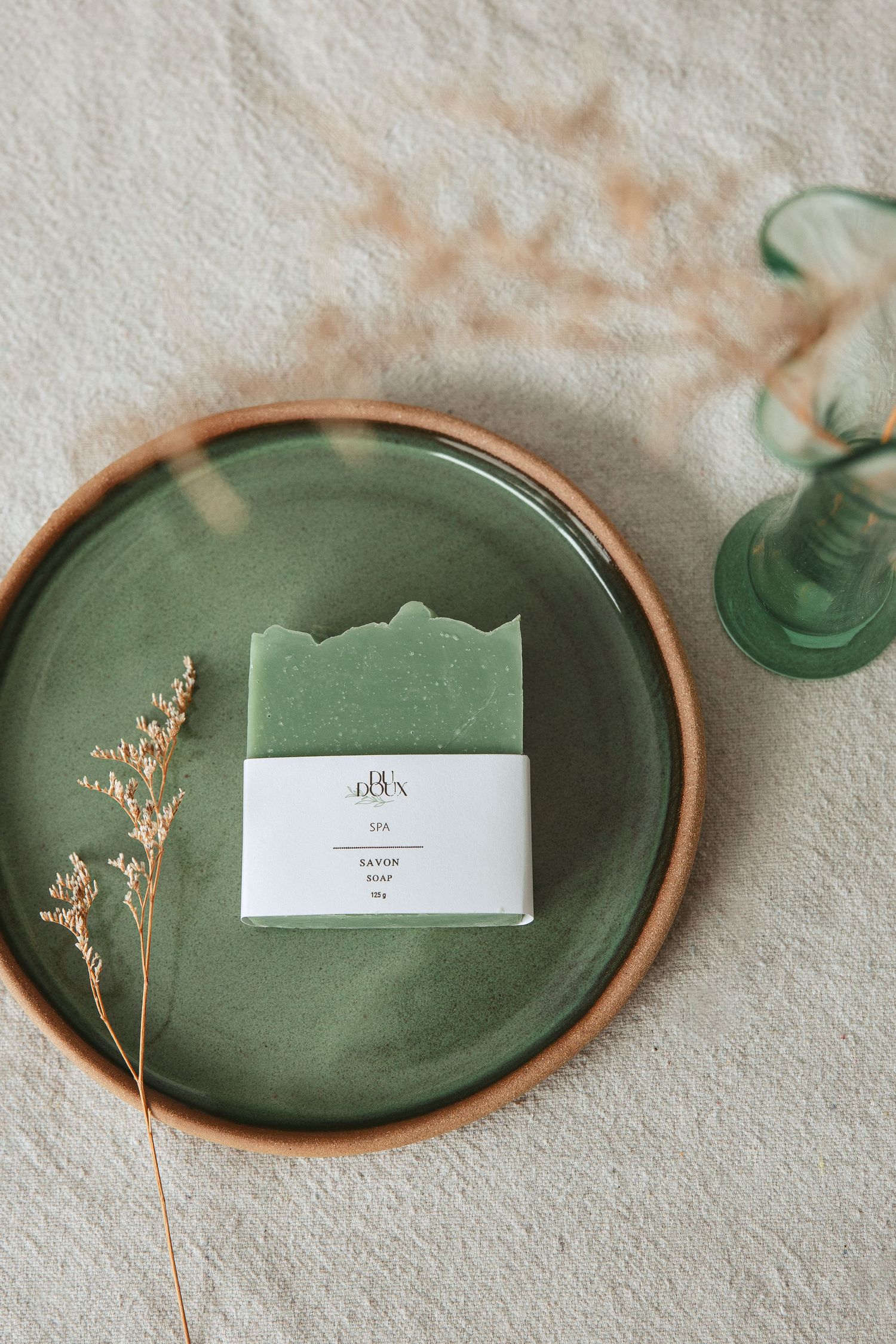 Green ceramic plates with delicate dried flowers and place cards arranged in an elegant table setting display.