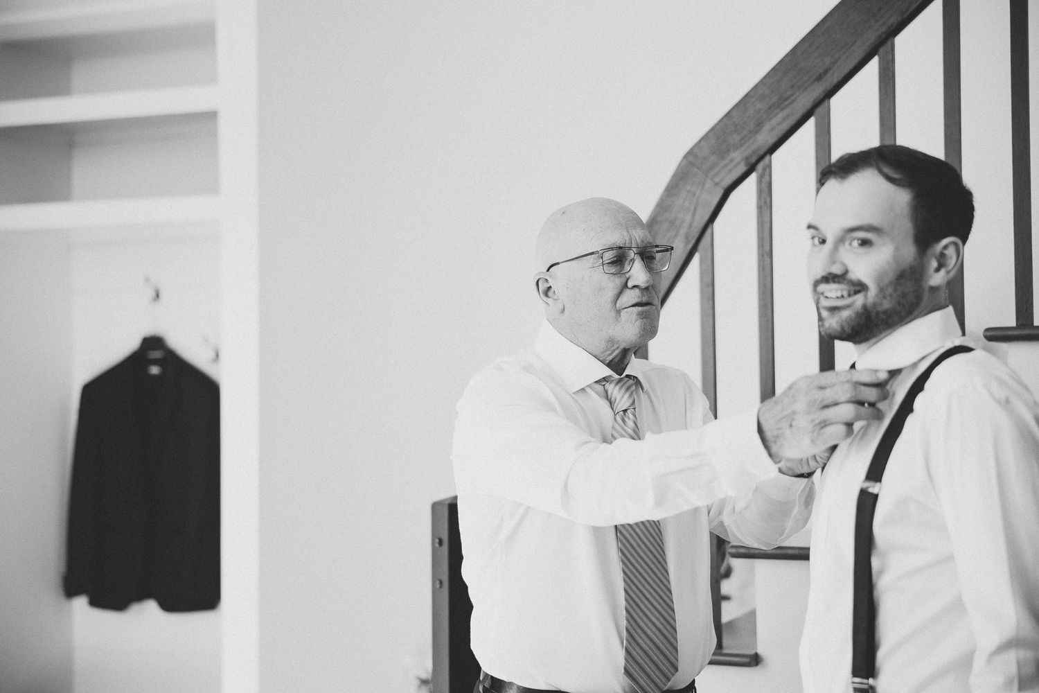 Black and white photo series showing a man in white shirt and tie getting dressed and putting on a suit jacket.