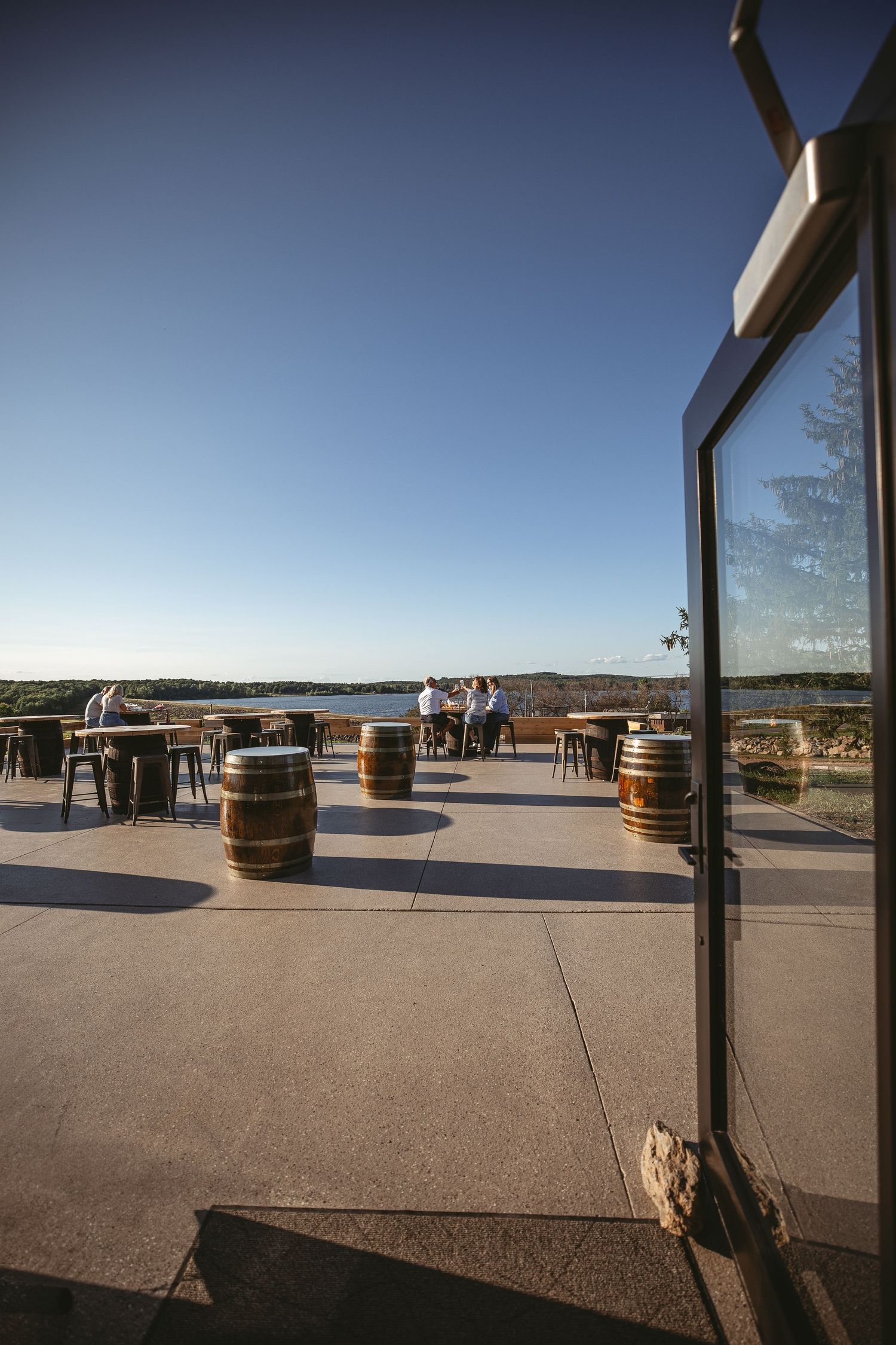 Outdoor patio with wine barrels and seating overlooking scenic vineyard landscape.