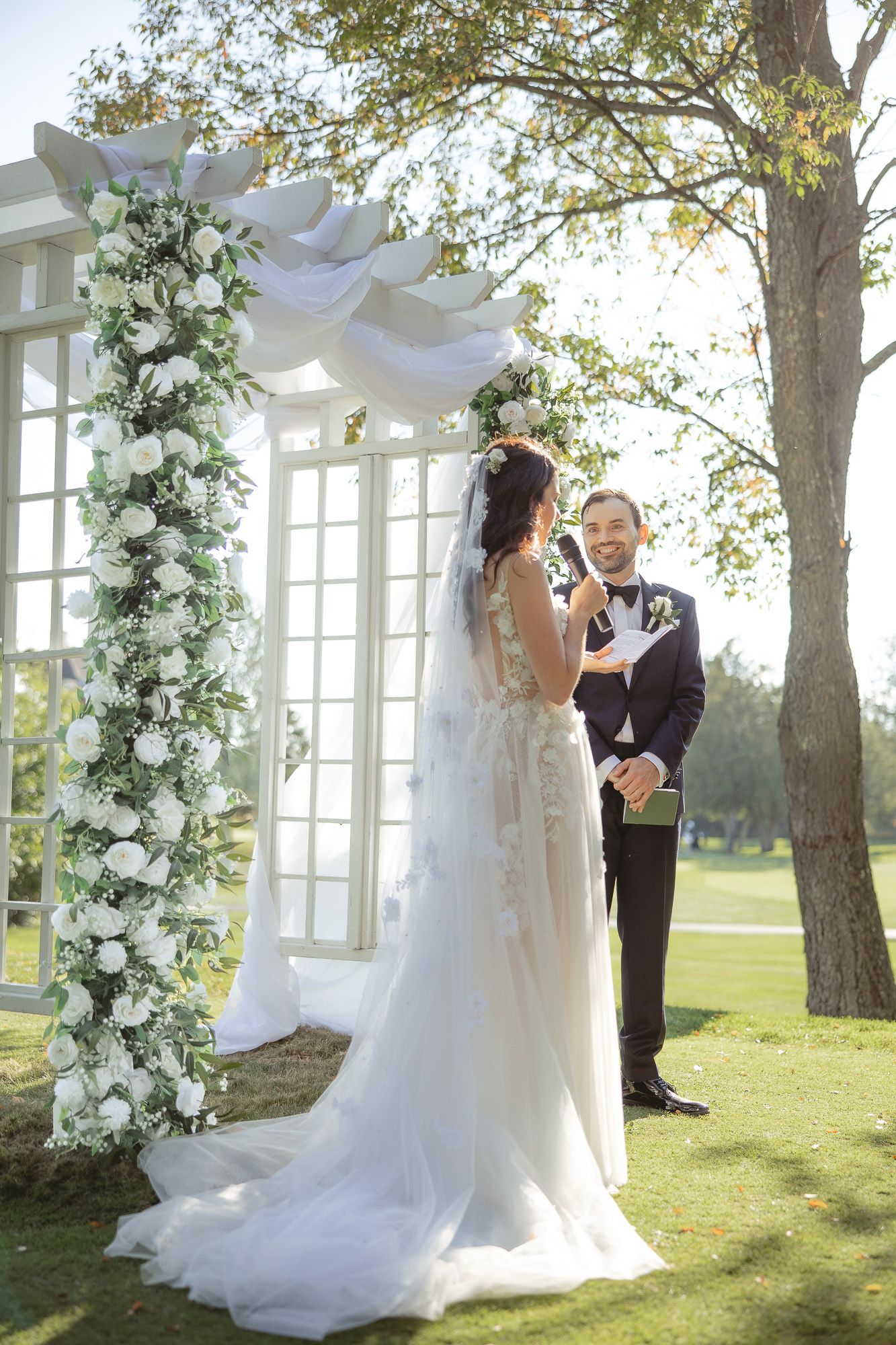 Cérémonie de mariage en plein air sur un terrain de golf ensoleillé, couple échangeant ses vœux sous un arbre, en Estrie