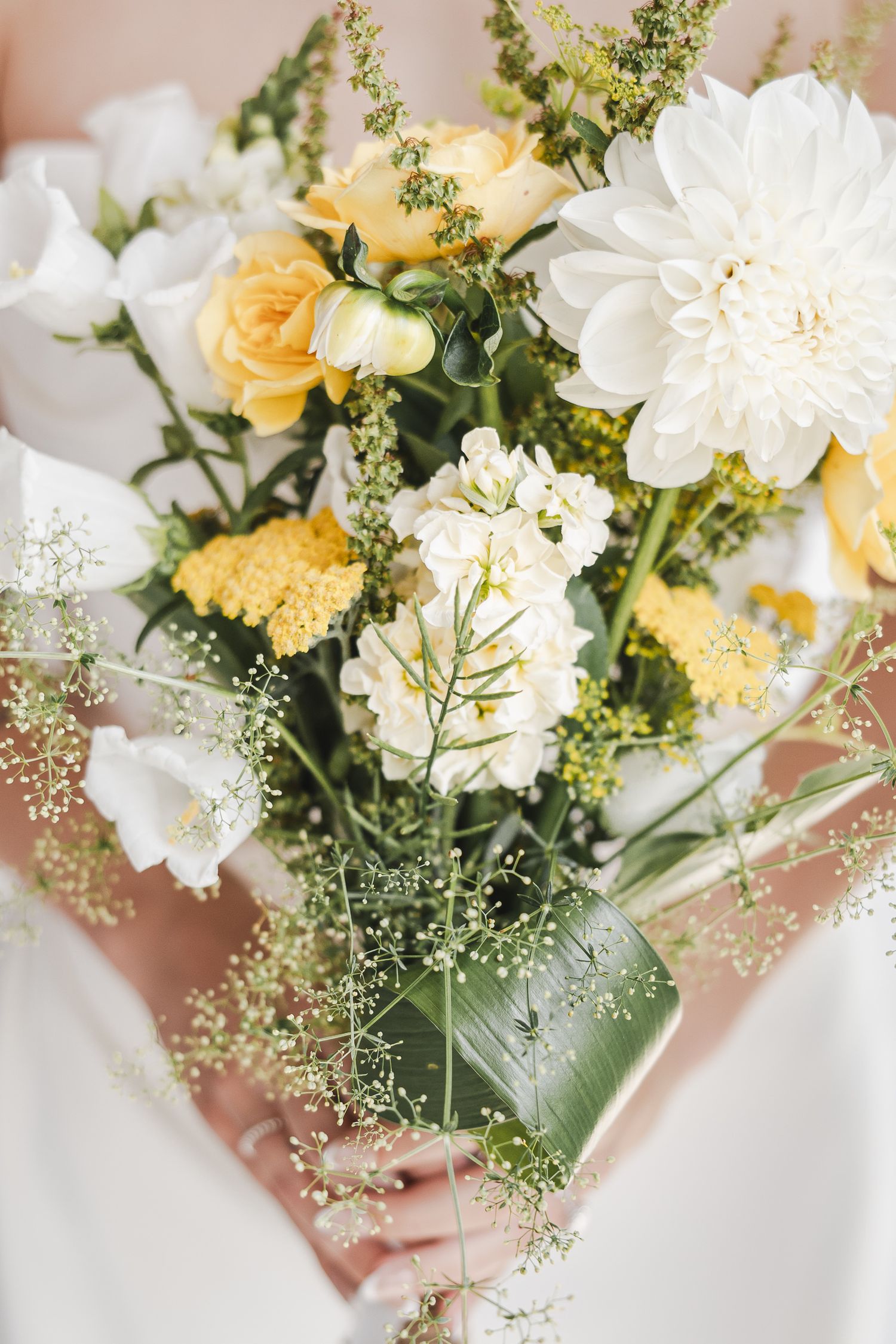 Bouquet de mariage élégant composé de fleurs blanches et jaune pâle, rehaussé de délicates touches de gypsophile