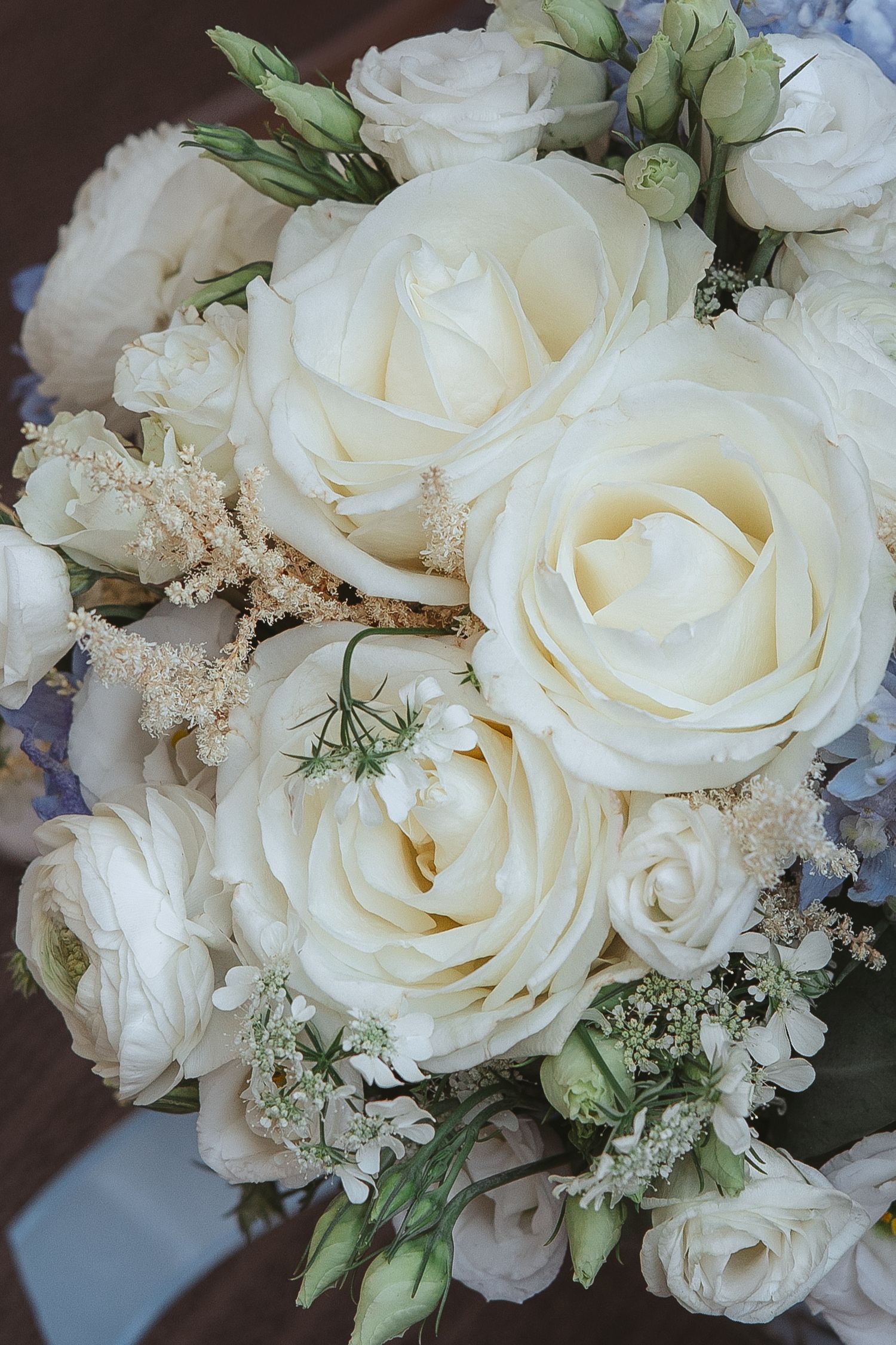 Bouquet de mariage de roses blanches élégantes, feuillage délicat et touches bleutées aux détails romantiques.