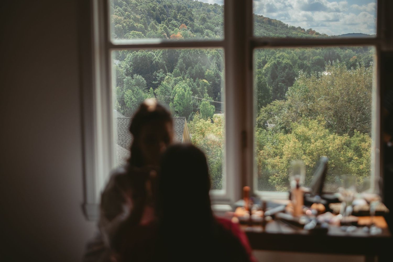 A large window in a room overlooks a scenic mountain landscape with trees and natural light streaming in.