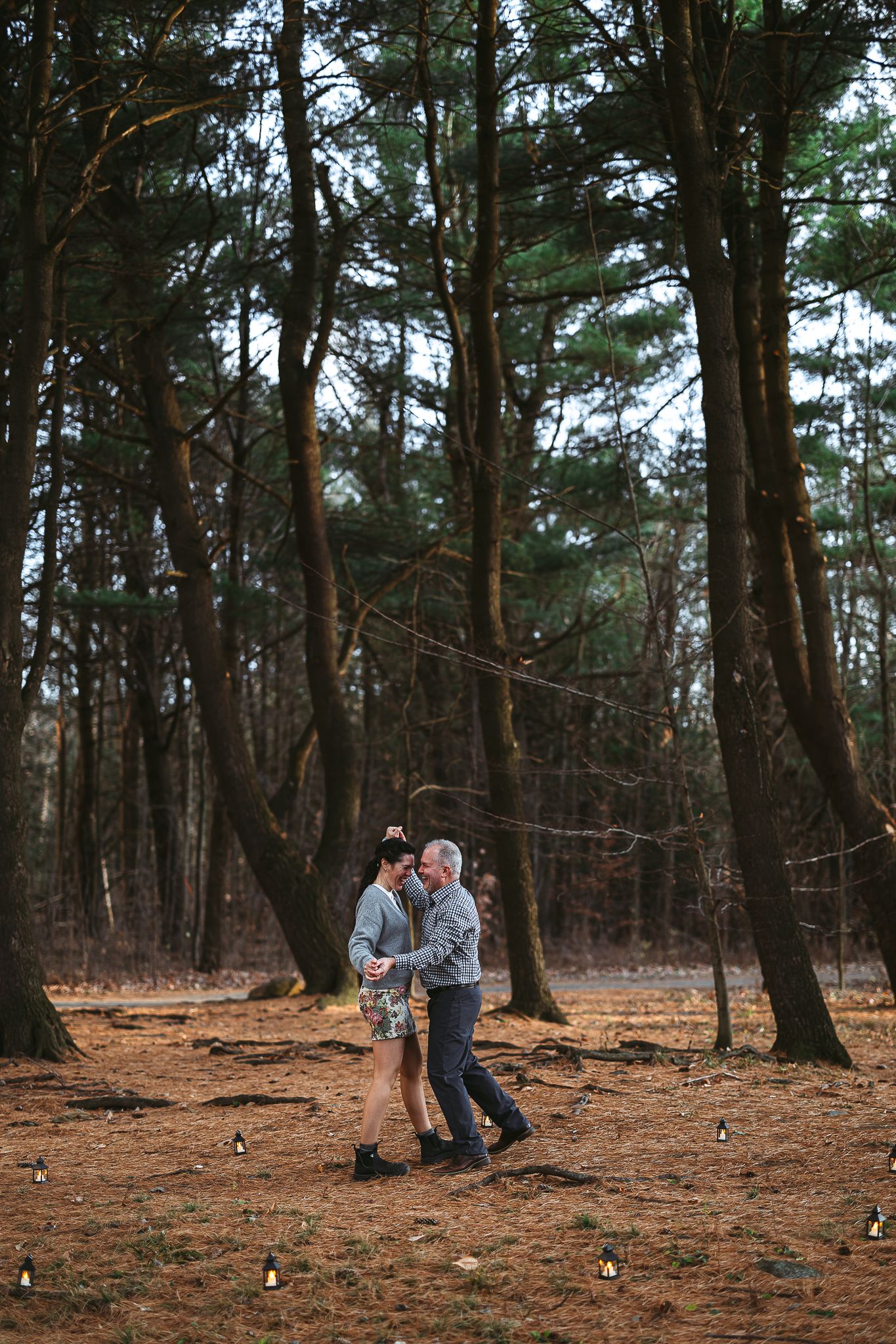 Couple célébrant mariage simple dans forêt de pins au crépuscule, bougies au sol, capturé pour moments intimes et atmosphère romantique
