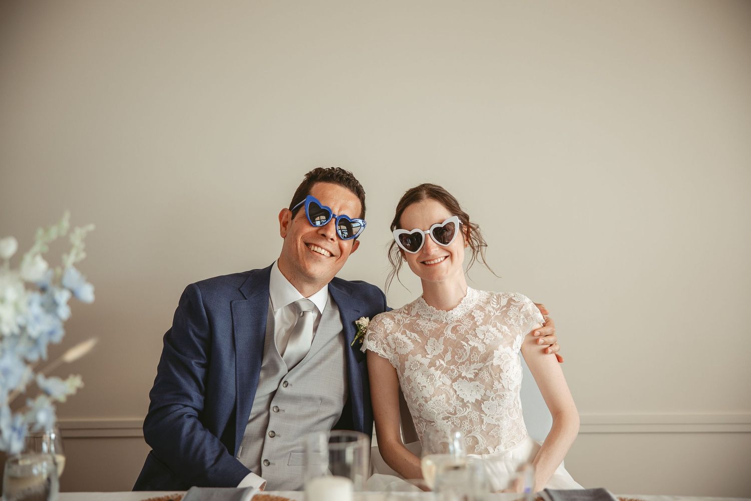 Les mariés fièrent avec des lunettes soleil en forme de coeur à la table d'honneur