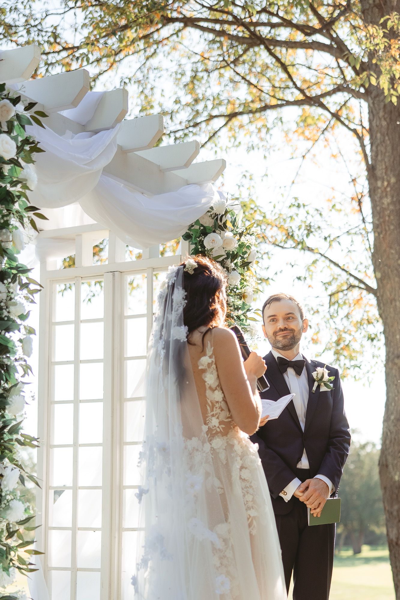 Cérémonie de mariage en plein air avec décor floral blanc et portes françaises créant une toile de fond élégante