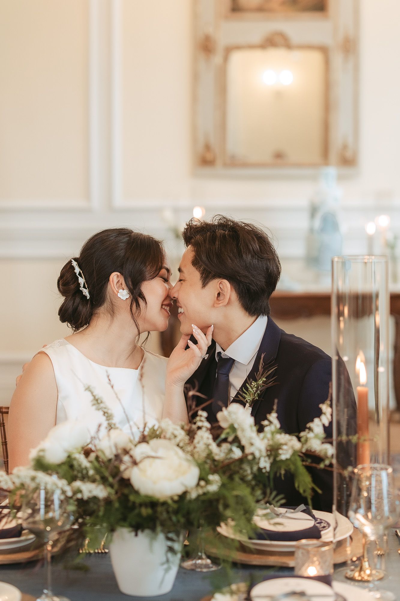 Mise en place de table de mariage élégante avec guirlandes de verdure, bougies et vaisselle, en lumière naturelle douce