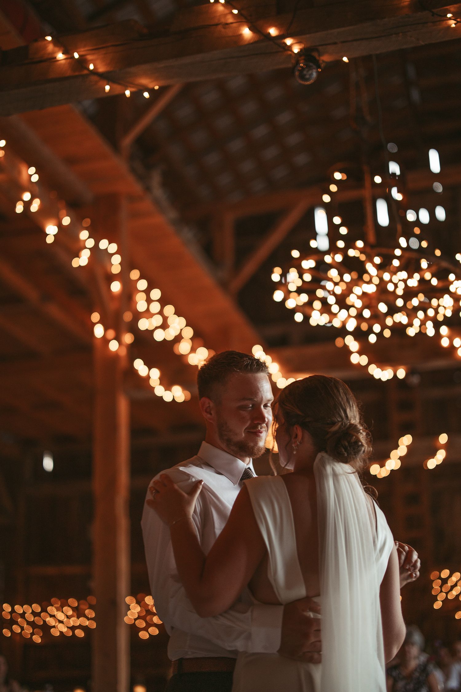 Première danse romantique sous des guirlandes lumineuses dans une grange rustique